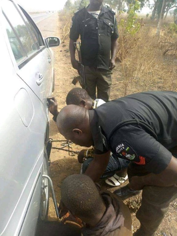 policemen help man fix car